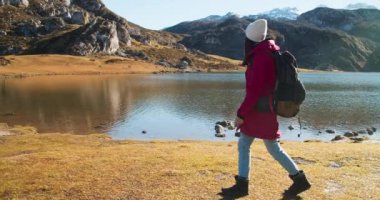 Travel photographer and influencer walks on mountain lake shore