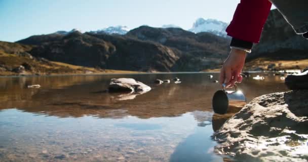 Caminante recoge beber agua del lago de montaña — Vídeo de stock