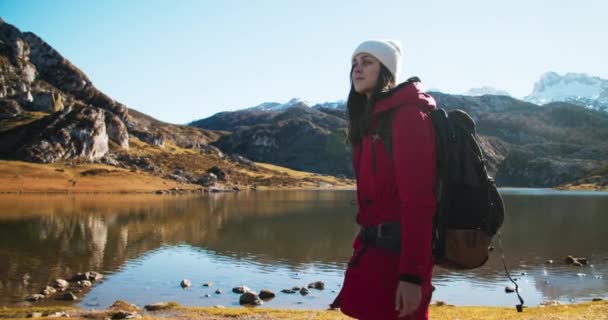 Travel photographer and influencer walks on mountain lake shore — Vídeo de stock