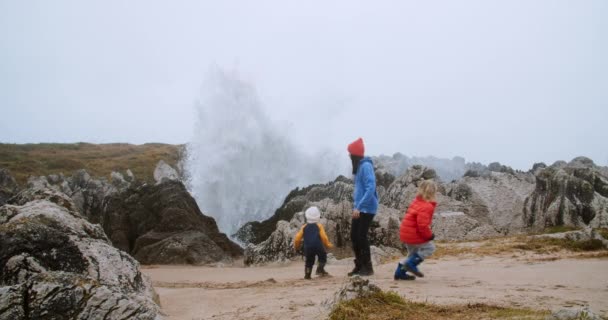 Родина розважається на березі океану з великими штормовими хвилями восени — стокове відео