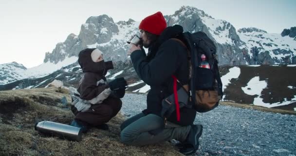 Hiker family sharing hot tea drink on his travel adventure to hight mountain — Vídeo de stock