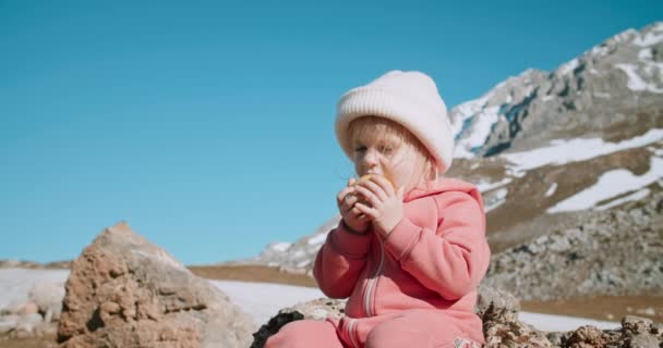 Linda niña se sienta y come manzana en la épica vista de la montaña — Vídeo de stock