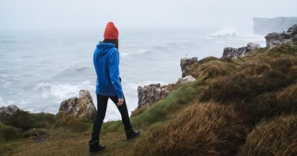 Молода жінка мандрівник гуляє по краю берегової скелі з видом на океан — стокове відео