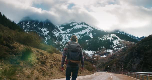 Emocionado joven caminar en el camino de montaña vacío levantando las manos con éxito — Vídeo de stock