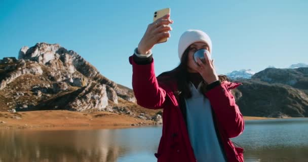 Traveler γυναίκα λήψη selfie χρησιμοποιώντας smartphone με φλιτζάνι ζεστό ρόφημα στο βουνό — Αρχείο Βίντεο