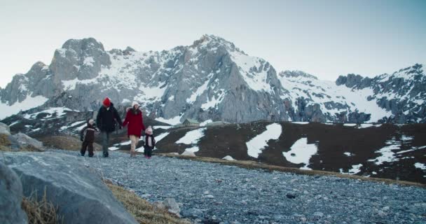 यात्री परिवार महाकाव्य पर्वत दृश्यों के साथ खाली देश सड़क पर चलता है — स्टॉक वीडियो