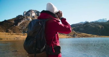 Göl kenarındaki destansı dağın fotoğrafını çeken genç bir kadının portresi.