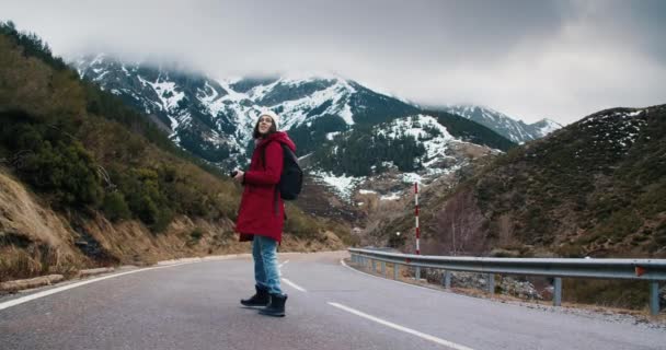 Young woman travel photographer walk on empty mountain road making photo — стоковое видео