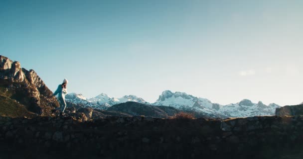 Young adult traveller woman crossing old bridge with epic mountain view — Stock Video