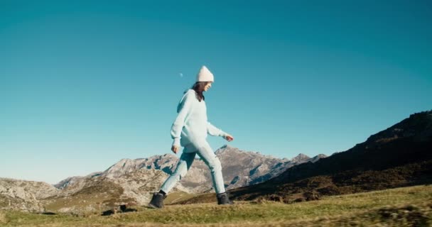 Excited young adult woman walk on top of hill with mountain view — Video Stock