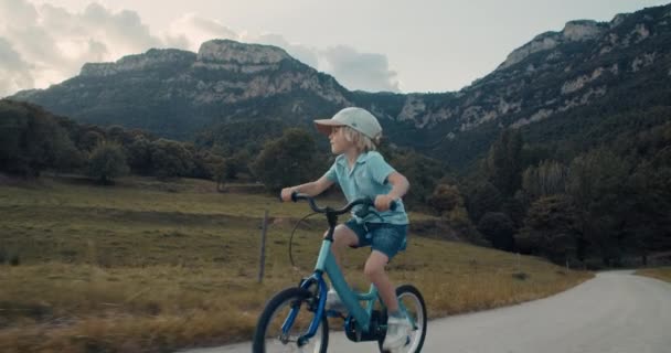 Счастливый Беззаботный Мальчик Катается Велосипеде Пустой Горной Дороге Вдоль Луга — стоковое видео