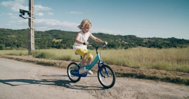 Счастливый Беззаботный Ребенок Катается Велосипеде Асфальтированной Дороге Вдоль Сельскохозяйственного Поля — стоковое видео