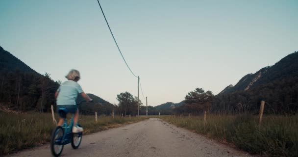 Fotocamera Seguire Bambino Bicicletta Sulla Strada Campagna Vuota Circondata Montagne — Video Stock