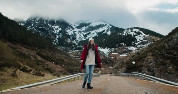 壮大な自然の風景に囲まれた空の山道を歩く赤いジャケットにインスピレーションを受けた幸せな女性 春のハイキングの旅の冒険に女性旅行者 興奮した女の子はアクティブな健康的なライフスタイルをリード — ストック動画