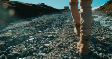 Düşük açılı el kamerası gezgin kadını takip ediyor. Kır yolundaki dağlara tırmanan bir kadın. Başarının yolu. Trek botları yakın çekim ve ayak sesleri. Açık havada aktif yaşam tarzı