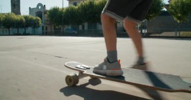 Kapalı çocuk bacakları yaz tatilinde uzun kaykay kayıyor. Çocuk spor sahasında kaykay öğreniyor. Çocuk aktif bir hayat sürüyor ve açık havada aşırı spor yapıyor. Haftasonu çocukluk