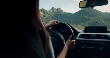 Heyecanlı bayan gezgin yolculuk macerasında yeni yerler keşfetti. Mutlu kadın gün batımında destansı manzarayla dağ yolunda araba sürüyor. Yaz tatilinde özgürlük kırsalda güneş doğarken