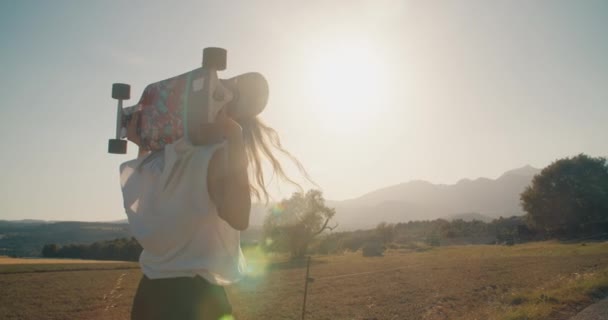 Modna Młoda Kobieta Spaceruje Polu Wiejskiej Drodze Trzymając Deskorolkę Zachodzie — Wideo stockowe