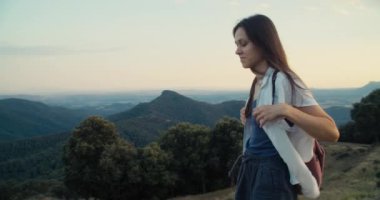 Günbatımında yaz yolculuğu macerasında dağın tepesinde yürüyen mutlu kadın gezginlerden ilham aldım. Yazın destansı manzarada güzel bir kadın yürüyüş yapar. Gençler akşamları sırt çantasıyla geziyorlar.. 