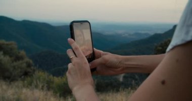 Woman hands closeup holding mobile phone on travel to mountains. Family making selfie picture on smartphone on summer hike journey. Happy mother with daughter smile and taking photo