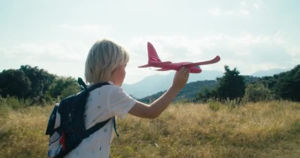 Cheerful and carefree child run holding toy airplane on mountain travel. Dreaming concept of childhood playing with aircraft. Medium shot of children on summertime hike adventure with backpack