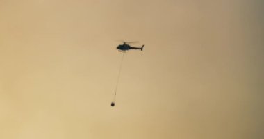 Firefighter helicopter flying on sky background through smoke. Wildfire on summertime caused by drought. 