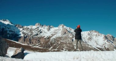 Man walk on top of mountain at snow in vacation travel and taking picture using smartphone. People using technology on nature at journey adventure. Make selfie with mobile phone on epic landscape