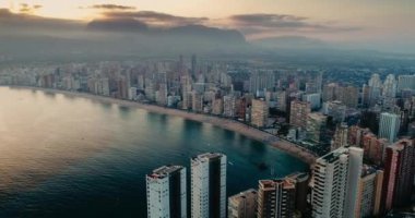 Aerial cityscape at sunset on evening. Urban footage of skyscrapers buildings along beach and sea shore. Concept of summer vacation and coast tourism. 