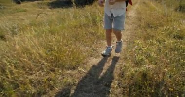 Unrecognizable children walking on mountain meadow on summer vacation travel. Closeup footsteps of child boy on hike journey. Active healthy lifestyle childhood on nature