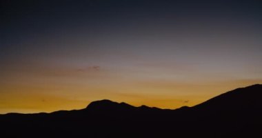 Sunset landscape of mountain silhouette with beautiful orange and dark blue sky panorama camera movement in slow motion. Background and copy space ready
