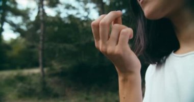 Female traveler on hiking adventure in forest eating wild growing blackberry organic blackberry. Young adult woman on summer vacation travel leads active healthy lifestyle