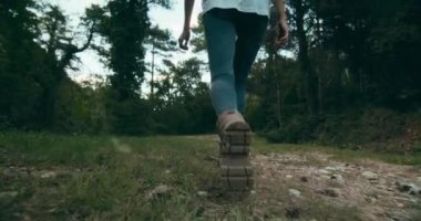 Low angle slow motion footage of young adult unrecognizable woman walk in hiking boots in forest on vacation travel. Active traveler on trekking adventure. 