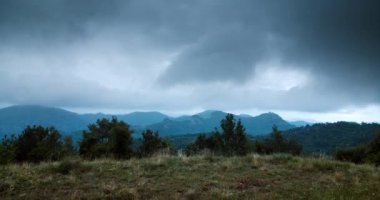 Dramatic sky with dark moving cloud to horizon and mountain peak. Grey rainy cloudscape in timelapse. Concept of bad weather during travel. 
