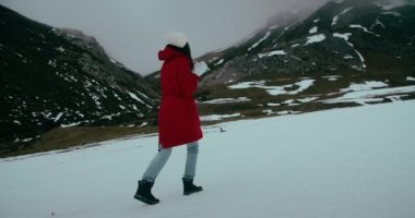 Bayan gezgin, kış tatilinde karda yürürken kırmızı ceketli, ağır çekimde çekilmiş bir macera yaşıyor. Bulutlu bir günde hafta sonu seyahatine çıkan neşeli, genç bir kadın. Yürüyüş parkurunda mutlu turistler