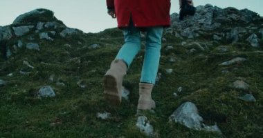 Dağ yolculuğundaki kadın gezgin elinde antika kamerayla dağa tırmanıyor. Genç kadın ayakları yavaş çekimde dağın zirvesine doğru yürüyor. Gezgin blogcu çekilecek manzara arıyor