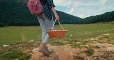 Sepet ve sırt çantasıyla gezintiye çıkmış kadın gezgin mantar arıyor ve topluyor. Tanımlanamayan bir kadın hafta sonu yolculuğunda turistik dağ yolunda yürüyor. Sağlıklı yaşam tarzı ve seyahat tutkusu.