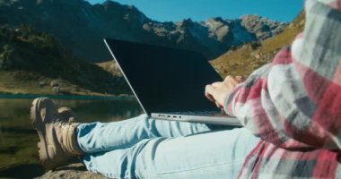 Tatil seyahatinde olan serbest bir kadın dağ kıyısında oturmuş dizüstü bilgisayarında destansı bir manzarayla daktilo yazıyor. Gezgin kadın macerası ofis dışına çıkmaya değer özgürlük hissi.. 