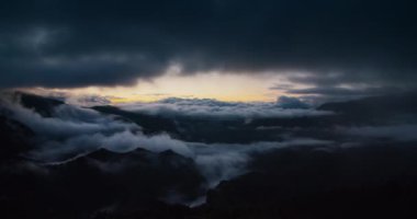 Dağ gezisinde destansı gün doğumunda dramatik bir sabah vaktidir. Vadide alçak bulutlar ve ufukta yükselen yüksek bulutlar.. 