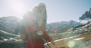 Kırmızı ceketli gezgin kadın kış yolculuğunda sırt çantasıyla dağ yolunda güzel manzaralı bir yürüyüş yapıyor.. 