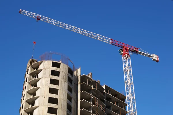 Um guindaste no fundo da casa em construção — Fotografia de Stock