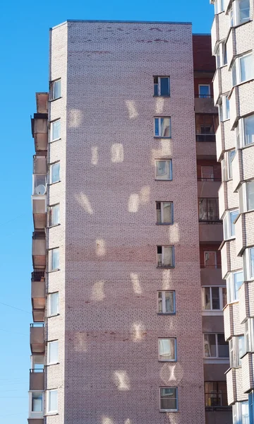 Солнечные лучи из окон на стене многоэтажного здания — стоковое фото