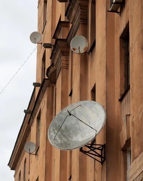 Several satellite dishes on rise old house — Stock Photo, Image