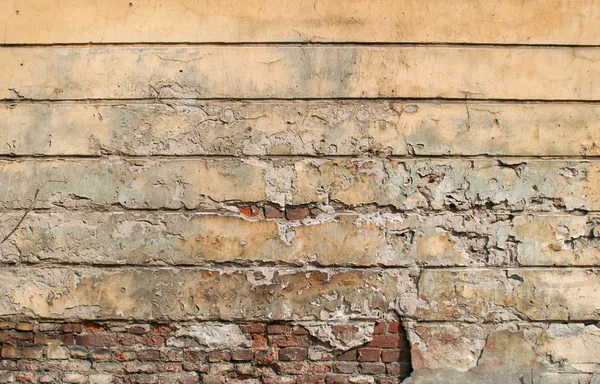 Textura de pared de ladrillo viejo cubierto con yeso amarillo — Foto de Stock