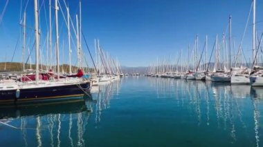 Türkiye, Fethiye, 06 Ekim 2021: Sabahları pek çok yelkenliyle yat limanı, pek çok gemi direği, açık güneşli havada sakin suda yansıyan yansımalar, ufukta dağlar