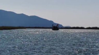 Türkiye 'de Dalyan' ın pitoresk körfezi, Fethiye yakınlarındaki adalardan birinin yanında, yolcu botları, arka planda dağlar, sallanan hindi bayrağı
