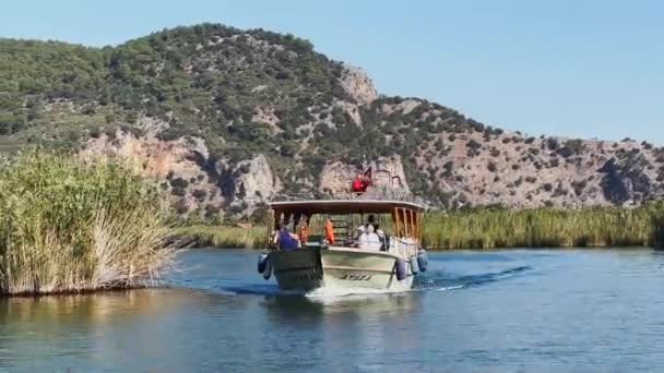 Törökország, Dalyan, 06 október 2021: A festői öböl Dalyan Törökországban, Caunos sírok a királyok mérföldkő, személyhajók, hegyek a háttérben, integető zászló pulyka — Stock videók