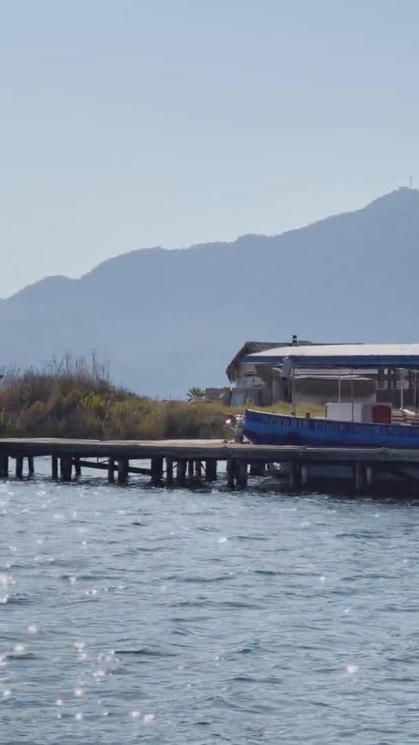 Turkije, Dalyan, 06 oktober 2021: De pittoreske baai van Dalyan in Turkije, Caunos Graven van de Koningen oriëntatiepunt, passagiersboten, bergen op de achtergrond, zwaaiende vlag van kalkoen — Stockvideo