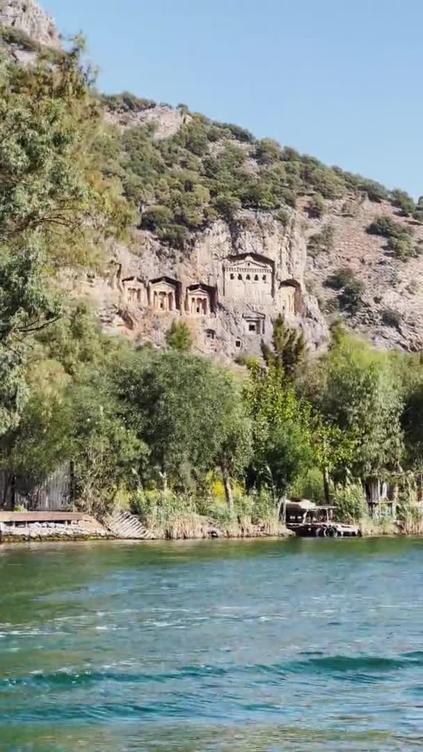 Monumento a las Tumbas de los Reyes de Caunos, Imágenes verticales del pintoresco paisaje del Parque Nacional de Dalyan en Turquía, barcos de pasajeros, montañas de fondo, ondeando bandera de pavo — Vídeo de stock