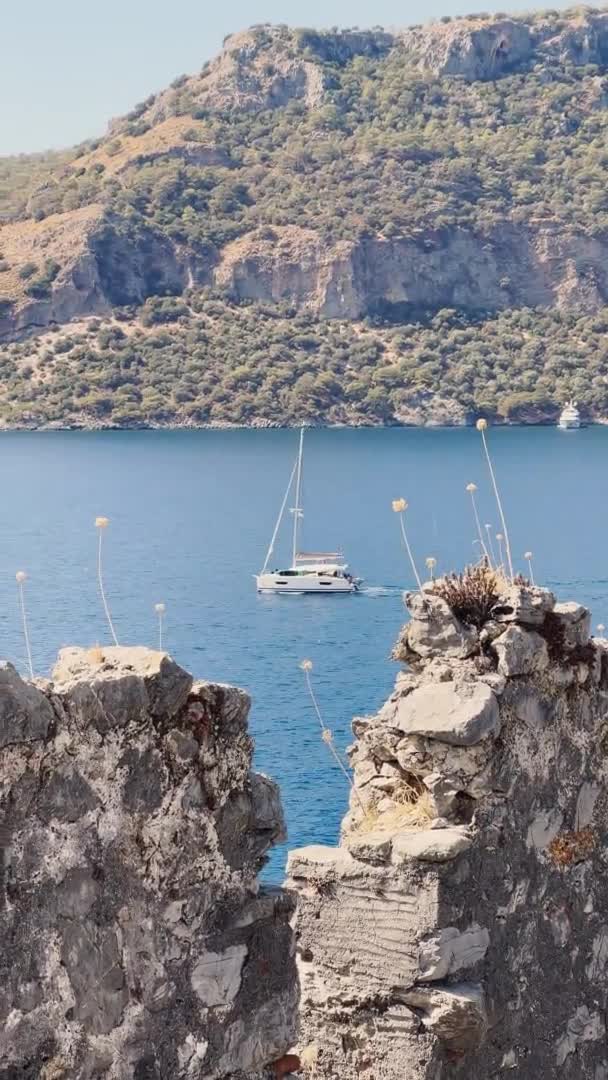 Nagranie pionowe malowniczej zatoki w pobliżu wyspy Gemiler, samotna żaglówka na morzu, wyspy w pobliżu Marmaris, regaty żaglowe, góry na tle, widok z góry w pogodę — Wideo stockowe