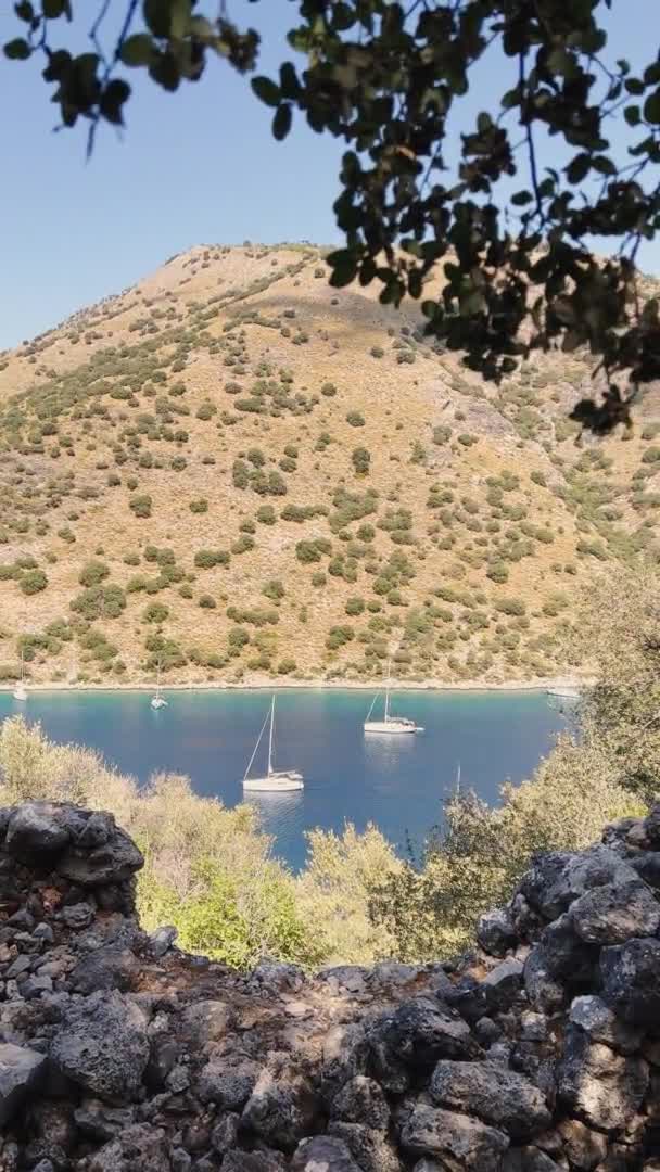 Les images verticales de la baie pittoresque près de l'île Gemiler, voilier solitaire en mer, îles près de Marmaris, régate de voile, montagnes en arrière-plan, vue sur le dessus par temps clair — Video